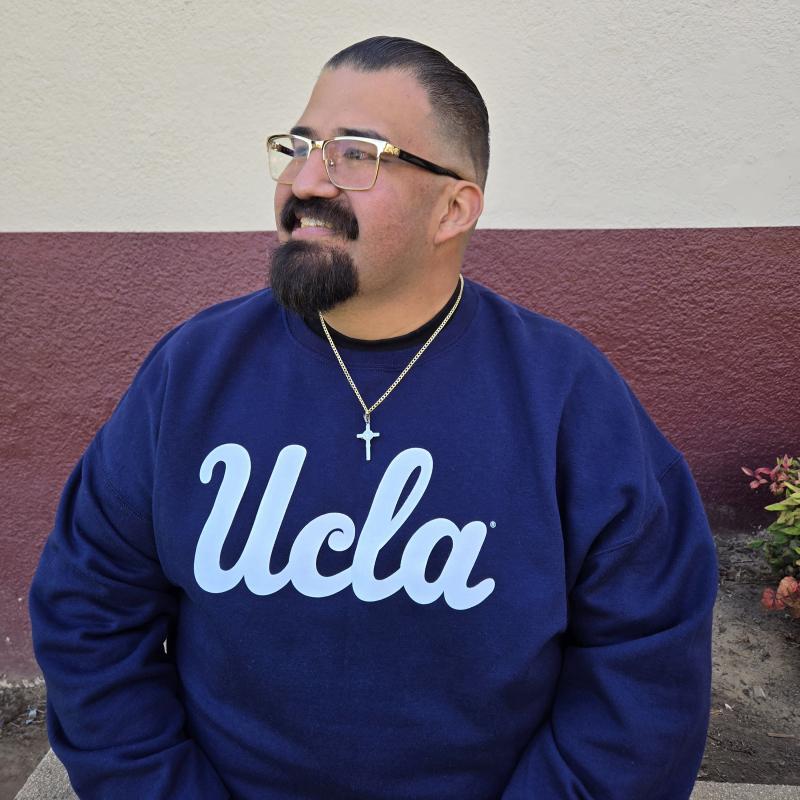 Man posing in blue UCLA Sweater